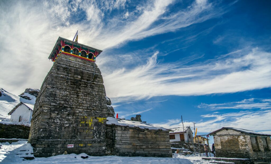 Snow-covered temple with vibrant decorations under a bright blue sky.